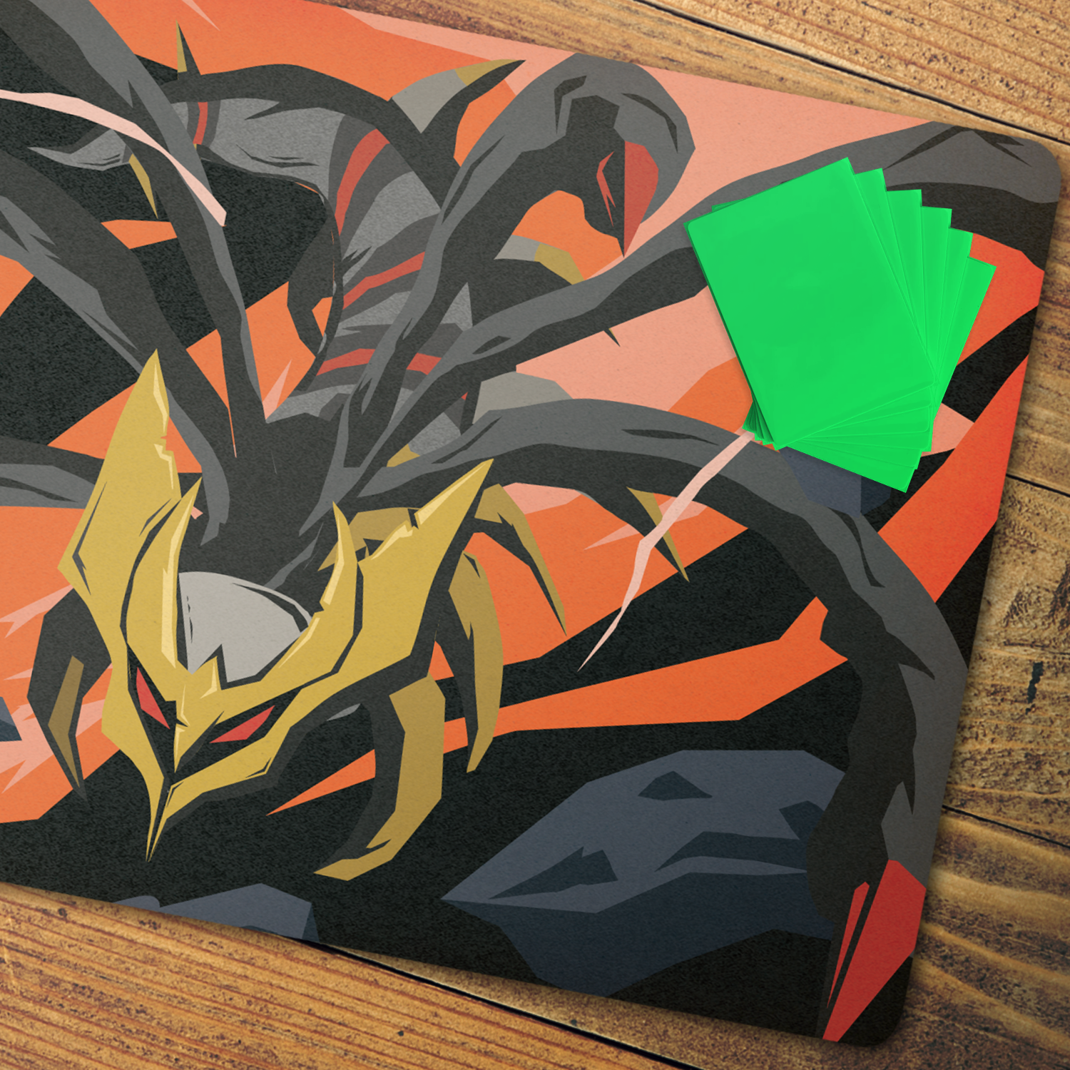 A close-up of a printed card or art piece featuring a stylized black spider-like creature with gold and red details against an orange and peach background, with a small fanned stack of bright green cards placed on top, all resting on a wooden surface.